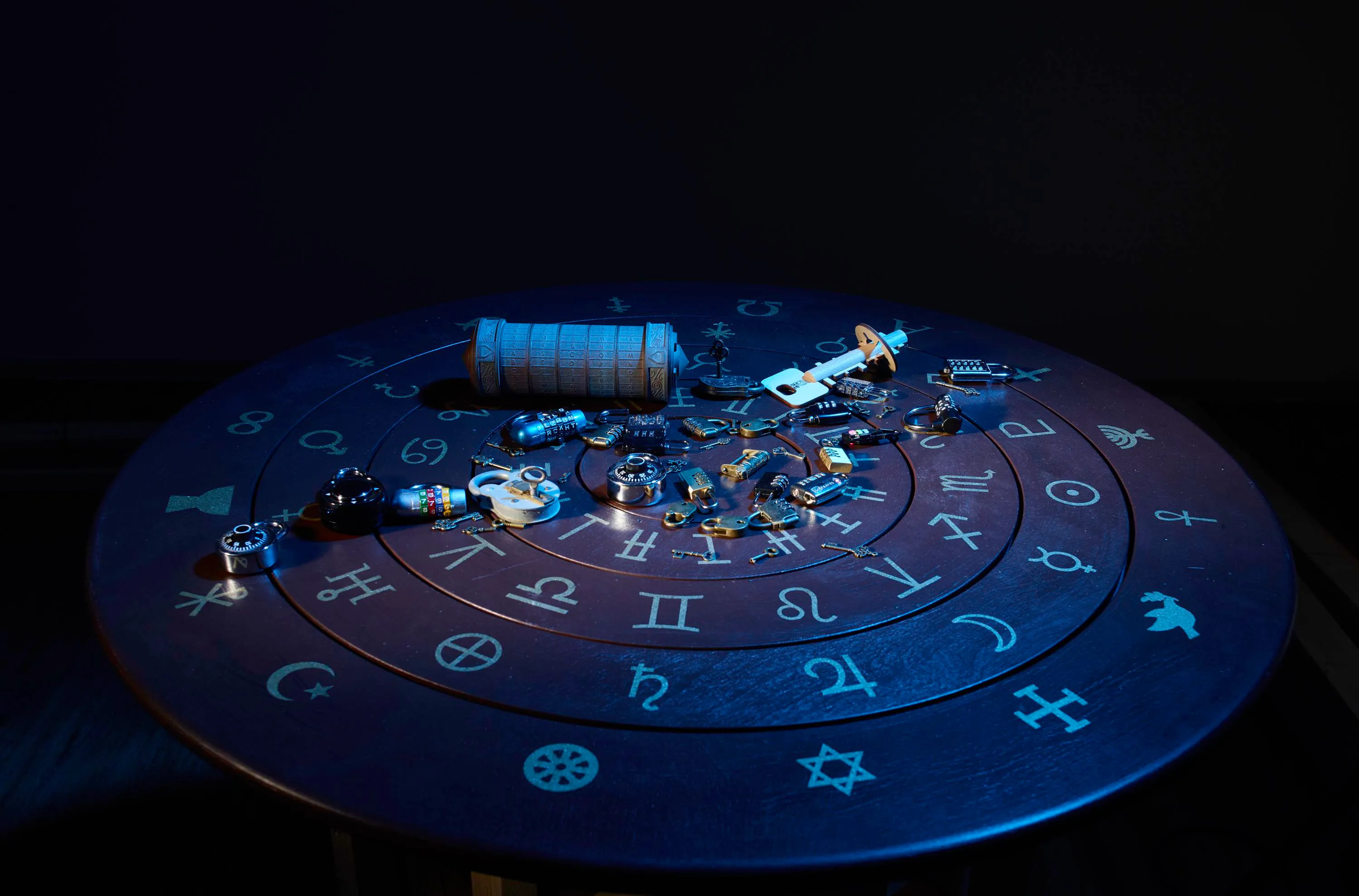 Schlösser, Schlüssel und ein Zylinder auf einem runden Tisch mit astrologischen Symbolen, blaues Raumlicht